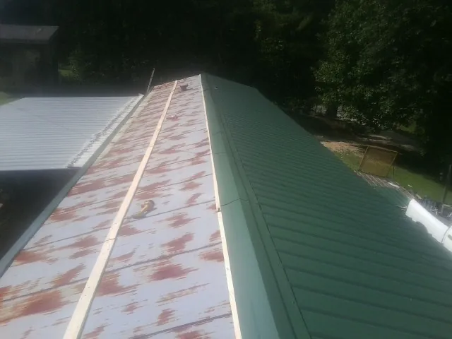 Old rusted panels beside newly installed green metal roofing — Wind Damage Roof Repair by Roofing Brothers in Harriman