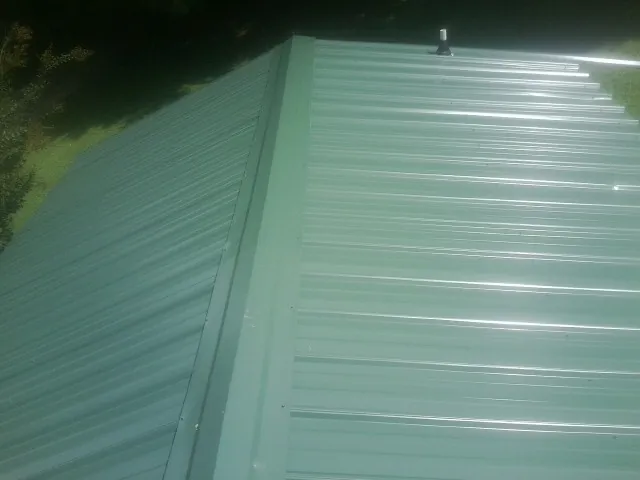 New green metal panels meeting at the ridge of a roof — Flat Roof Repair work by our crew in Harriman
