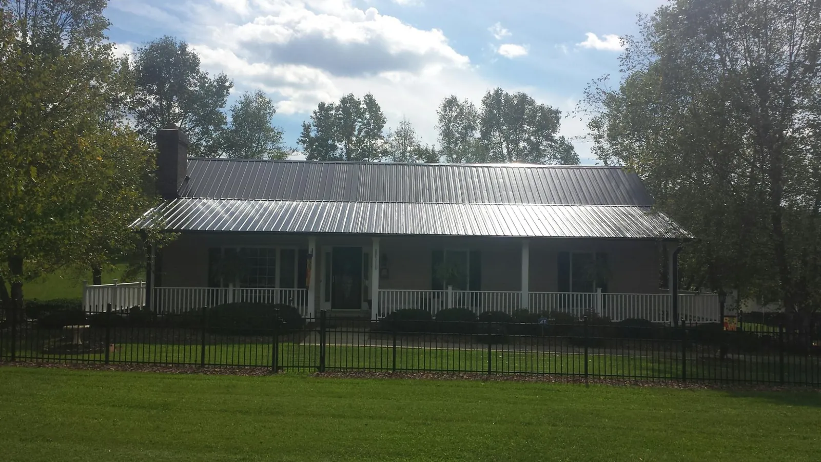 Gray metal roof on a brick ranch with a full width front porch — Gutter Guard Installation work by our crew in Harriman