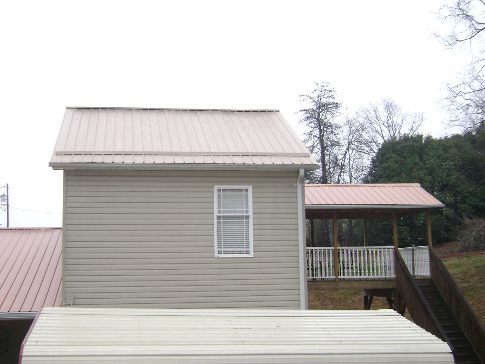 Tan metal roofs on a two story addition and attached porch, from a Roof Replacement job in Harriman